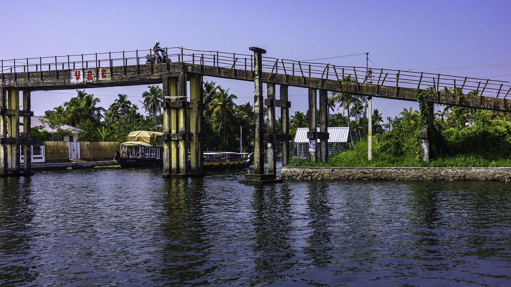 Houseboat passing under a low canal bridge, backwater village, Alleppey
