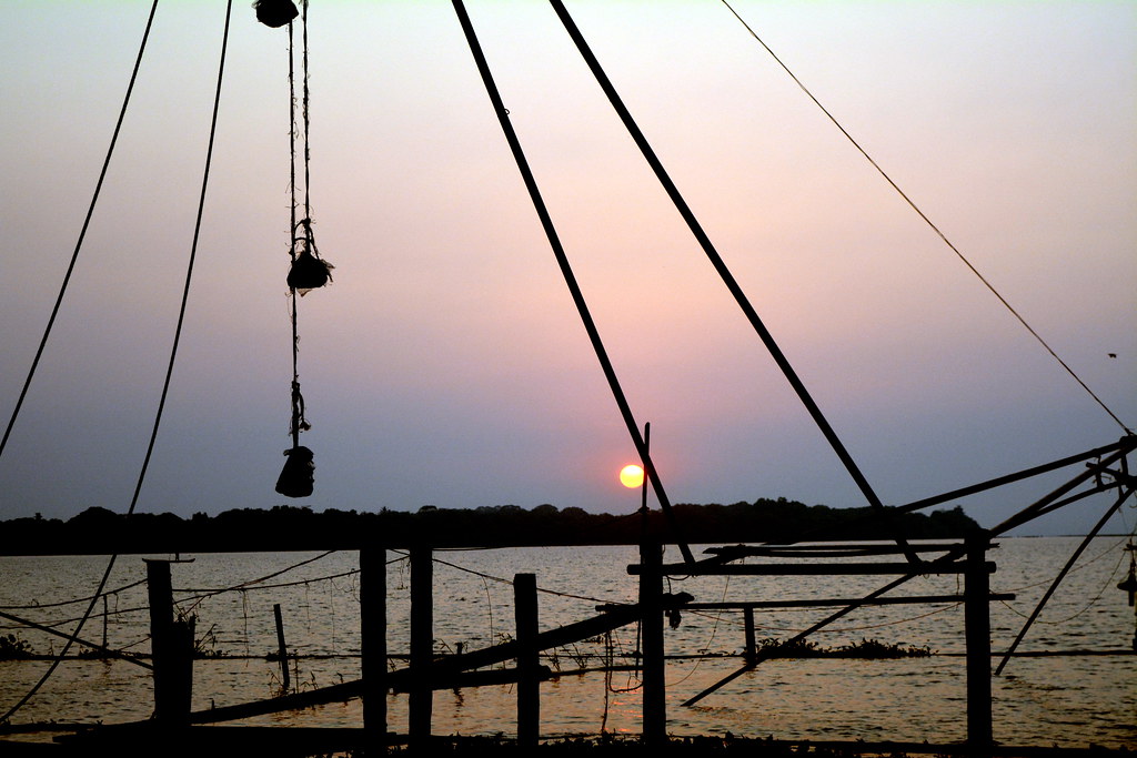 Chinese fishing nets silhouetted against a pink sunset sky, Alleppey backwaters