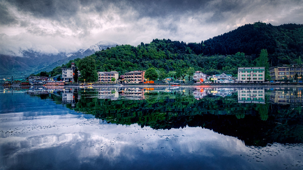 Srinagar town and forested hills perfectly reflected in the still waters of Dal Lake at dusk