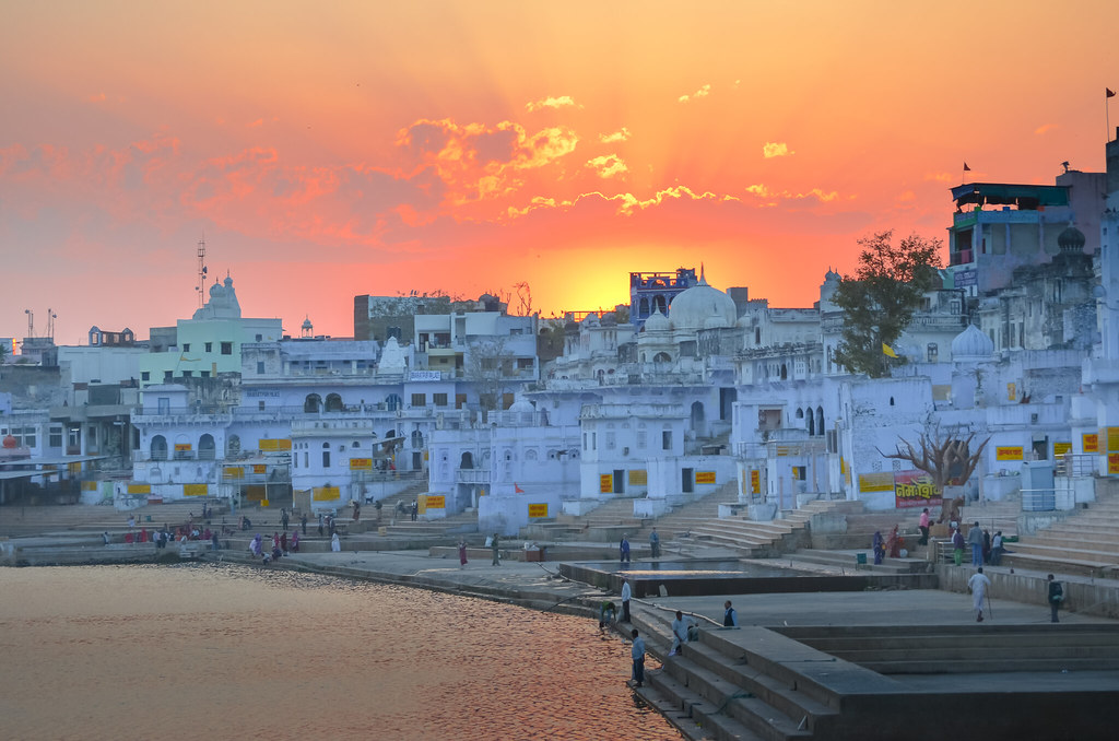Sunset over Pushkar Lake, the sky burning orange above the white-washed temple ghats lining the sacred water
